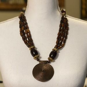 Brown beaded necklace with solid metal medallion.